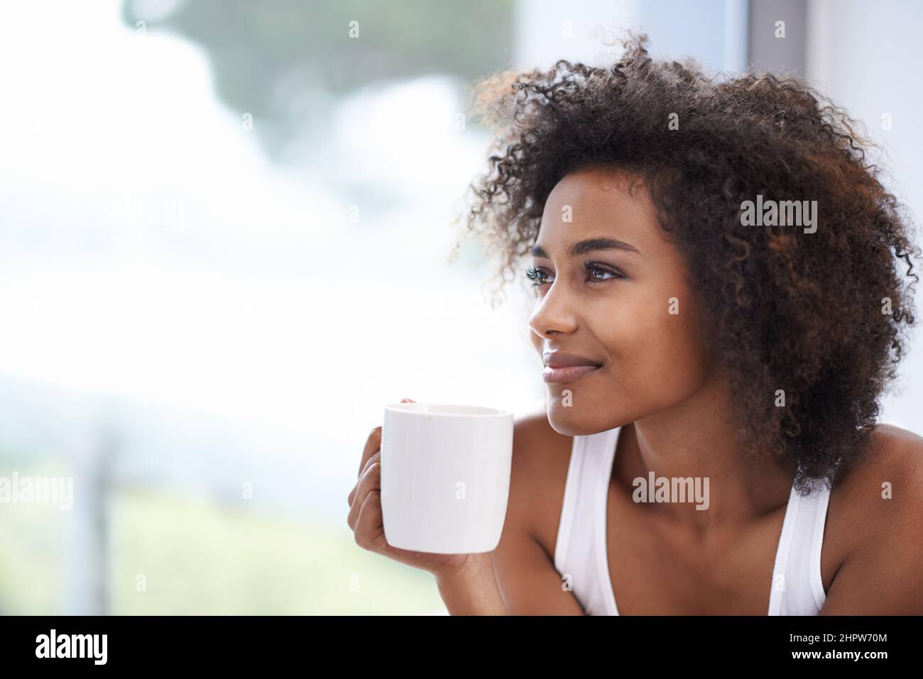 L'odeur apaisante du café du matin. Photo courte d'une jeune femme en train de savourer une tasse de café. Banque D'Images