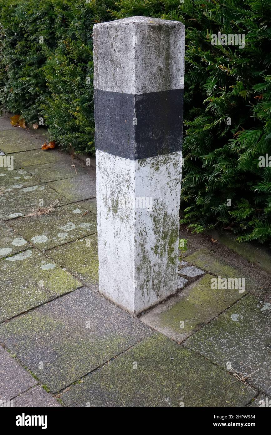 Poteau en béton noir et blanc de mousse dans la conception d'un poteau de réflecteur allemand devant un buisson vert, Hildesheim, Basse-Saxe, Allemagne Banque D'Images