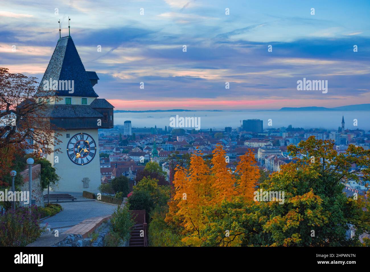 Paysage urbain de Graz et célèbre tour d'horloge (Grazer Uhrturm) sur la colline de Schlossberg, Graz, Styrie, Autriche, en automne, au lever du soleil Banque D'Images