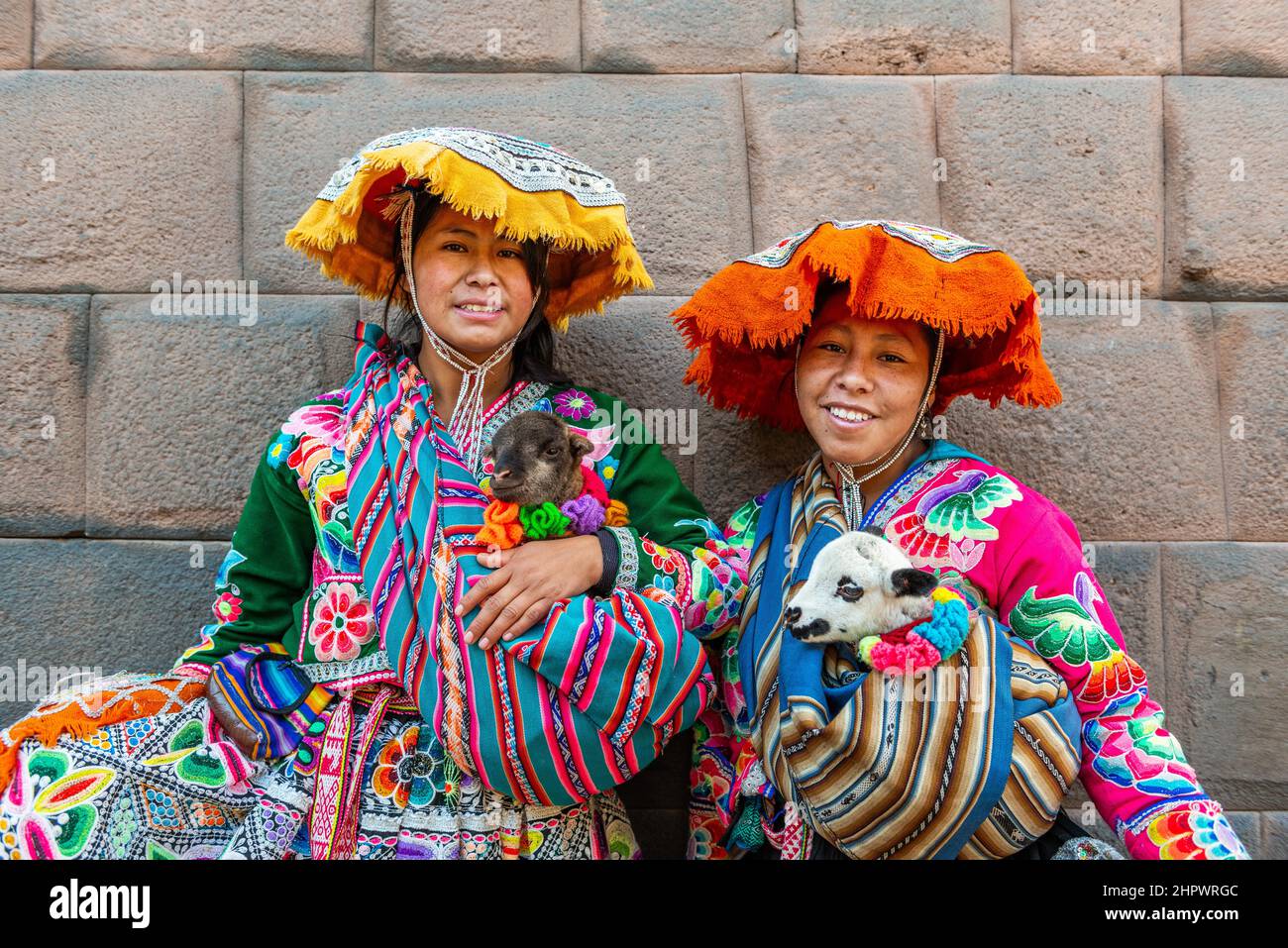Deux femmes inca en costume traditionnel avec agneaux devant un mur inca, Cusco, Pérou Banque D'Images