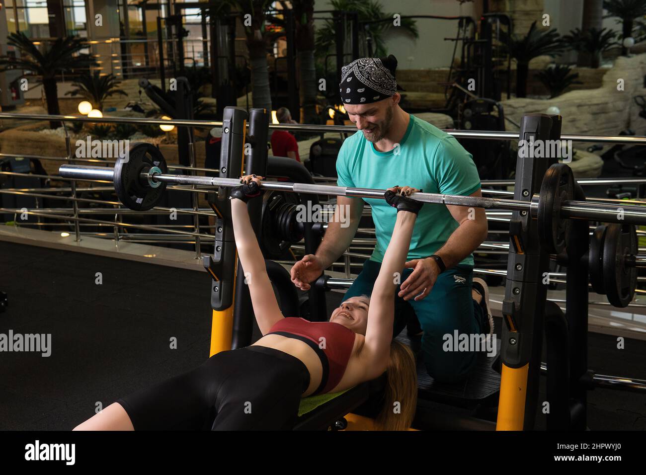 L'entraînement dirigé par un instructeur aide un beau client à effectuer des exercices dans un club de remise en forme, le concept de jouer du sport avec un loisir professionnel de gym Banque D'Images