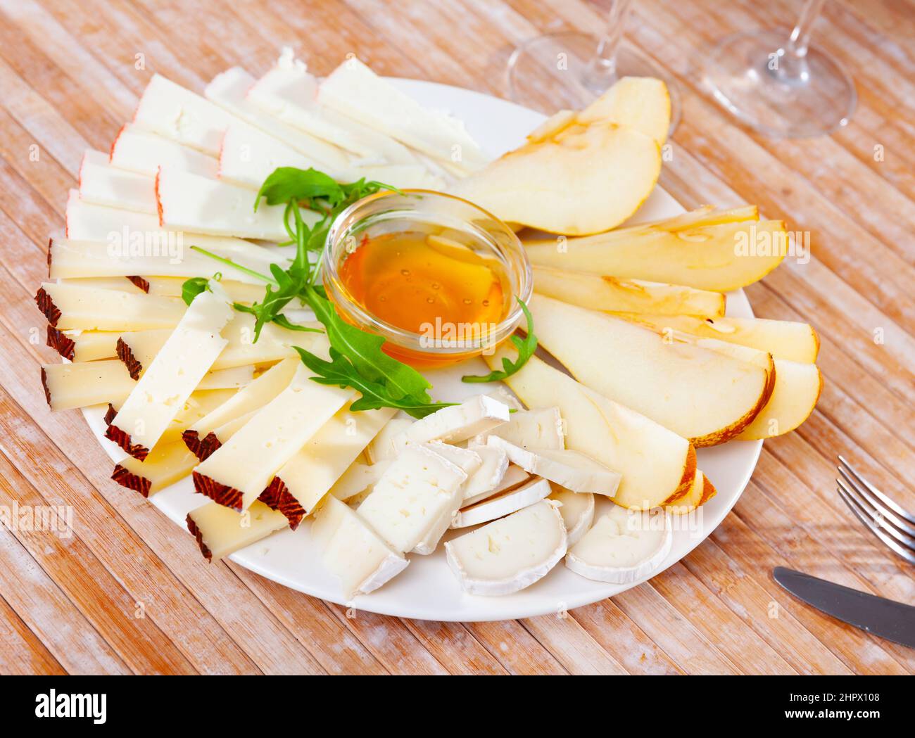 Assiette avec différents types de fromage et une tasse de miel Banque D'Images