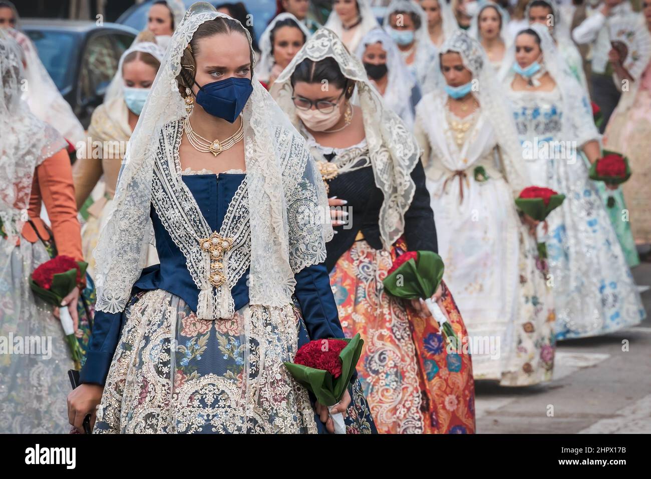 Valence, Espagne - 4 septembre 2021 : femmes avec masques pour la protection des covid et robes florales traditionnelles marchant pour la parade à la celebbratio Banque D'Images