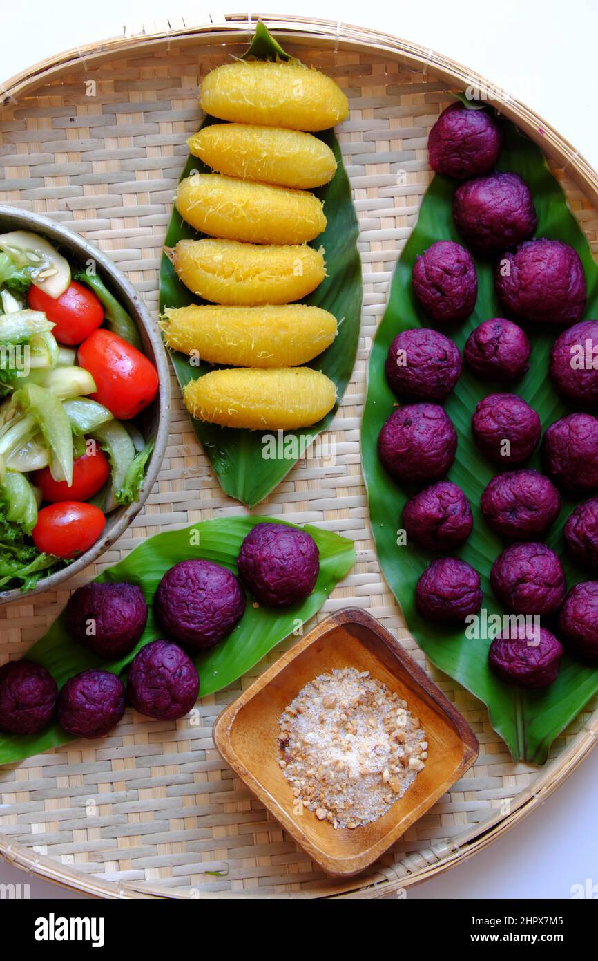 Plateau avec vue sur le dessus de la nourriture végétalienne de la patate douce violette, de la banane bouillie et de la salade avec de la tomate pour un dîner simple, un menu sans viande sera bon pour la santé Banque D'Images