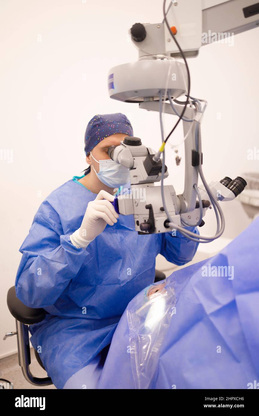 Médecin utilisant un microscope chirurgical pendant son opération sur son patient Banque D'Images