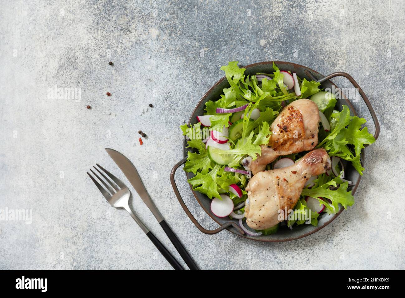 Saine alimentation propre. Viande et salade fraîche. Des pilons de poulet cuits et une salade végétalienne verte faite à partir d'un de feuilles vertes et de légumes de printemps sur un s. Banque D'Images