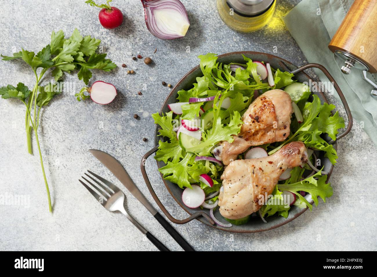Saine alimentation propre. Viande et salade fraîche. Des pilons de poulet cuits et une salade végétalienne verte faite à partir d'un de feuilles vertes et de légumes de printemps sur un s. Banque D'Images