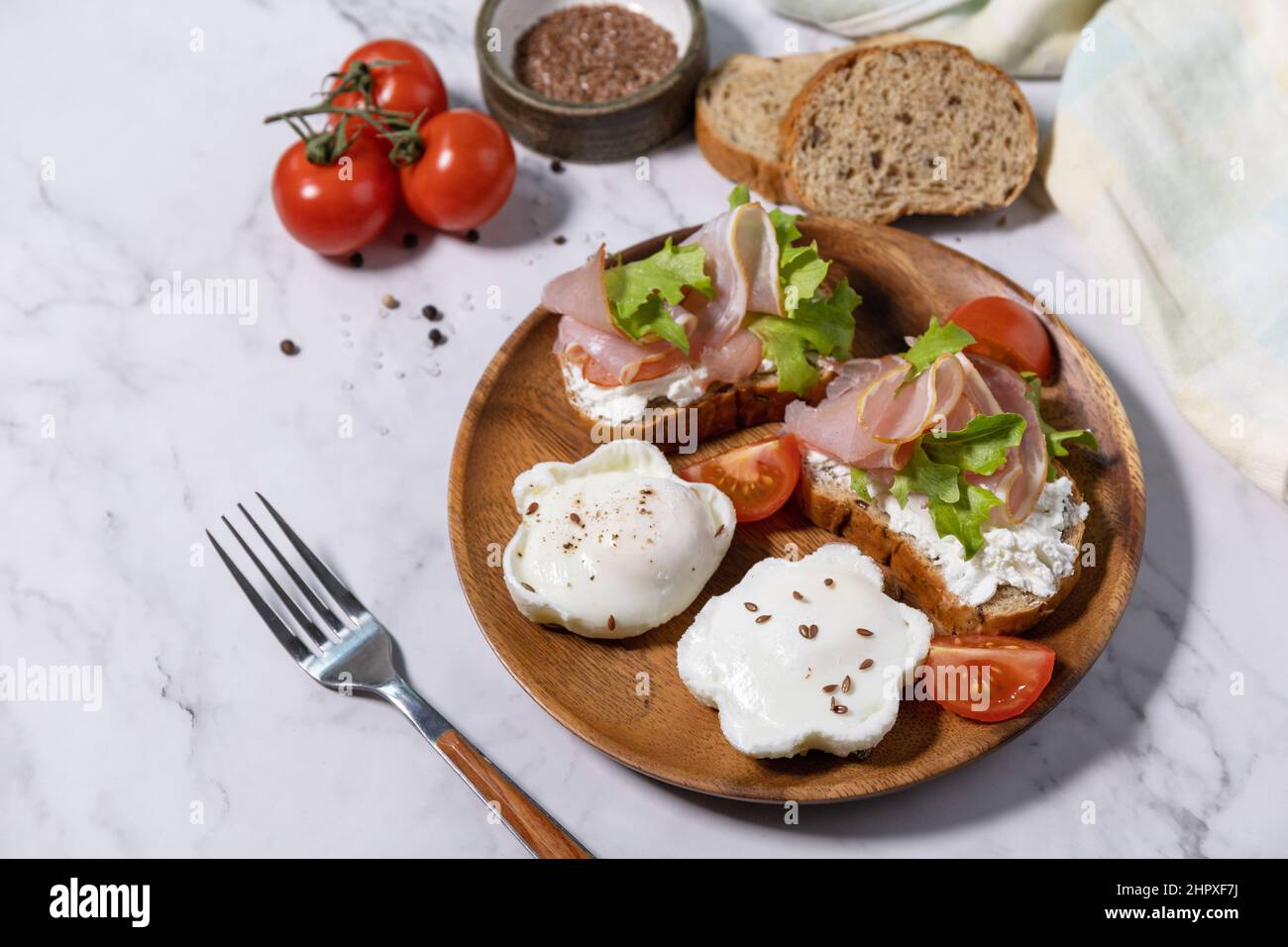Petit-déjeuner ou brunch de Pâques. Délicieux petit déjeuner ou en-cas - œufs pochés et fromage à la crème pain de seigle complet, prosciutto, arugula sur un t de marbre Banque D'Images