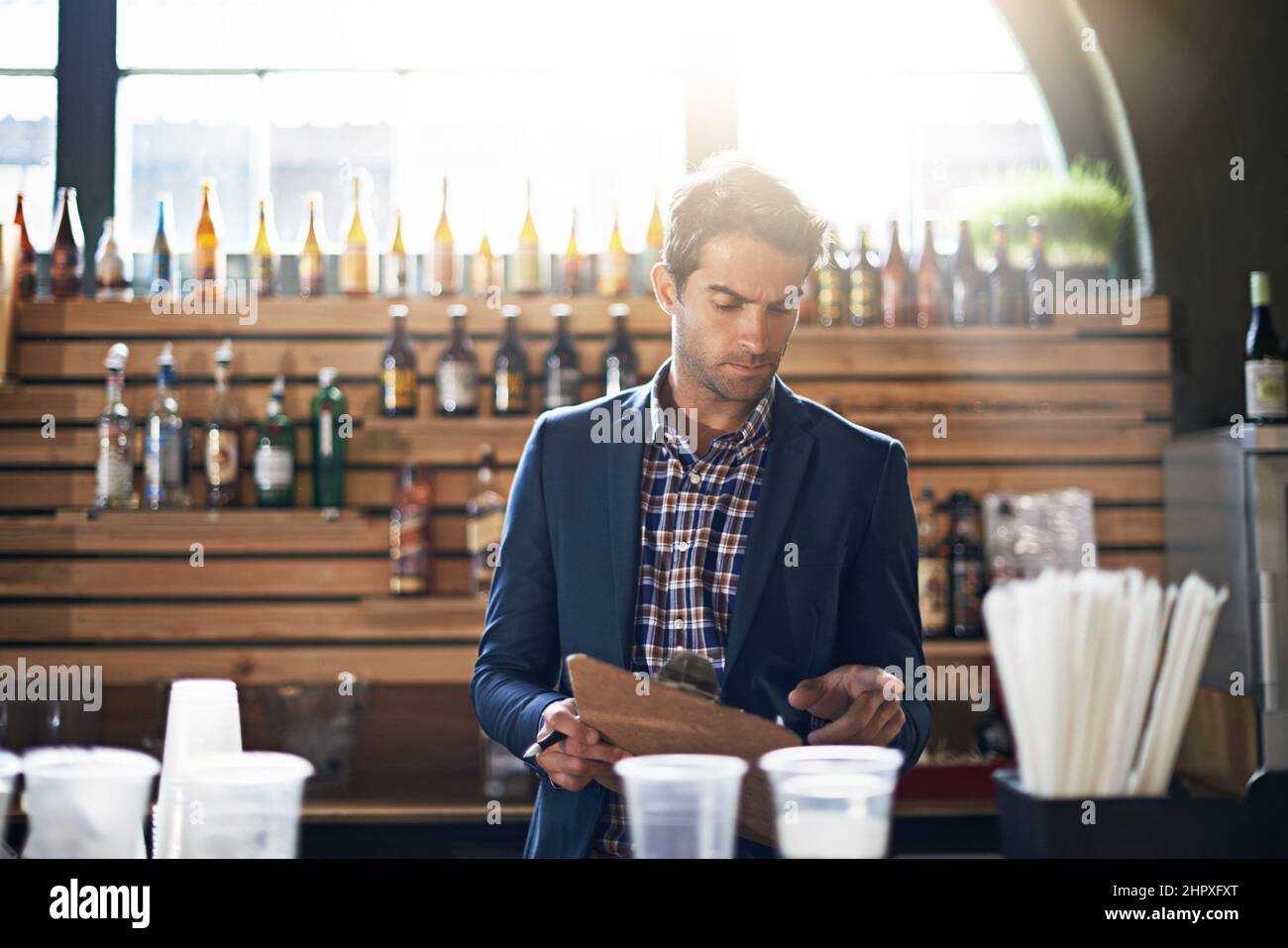 Est ce droit. Photo rognée d'un propriétaire de bar mâle vérifiant ses fournitures et son stock. Banque D'Images