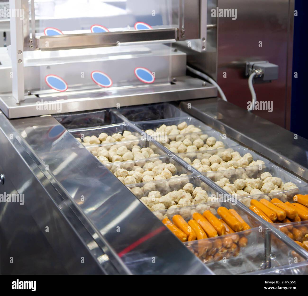 Emballage de boule de viande et de saucisse sur la machine de scellement d'emballage sous vide alimentaire dans l'usine industrielle alimentaire. Banque D'Images