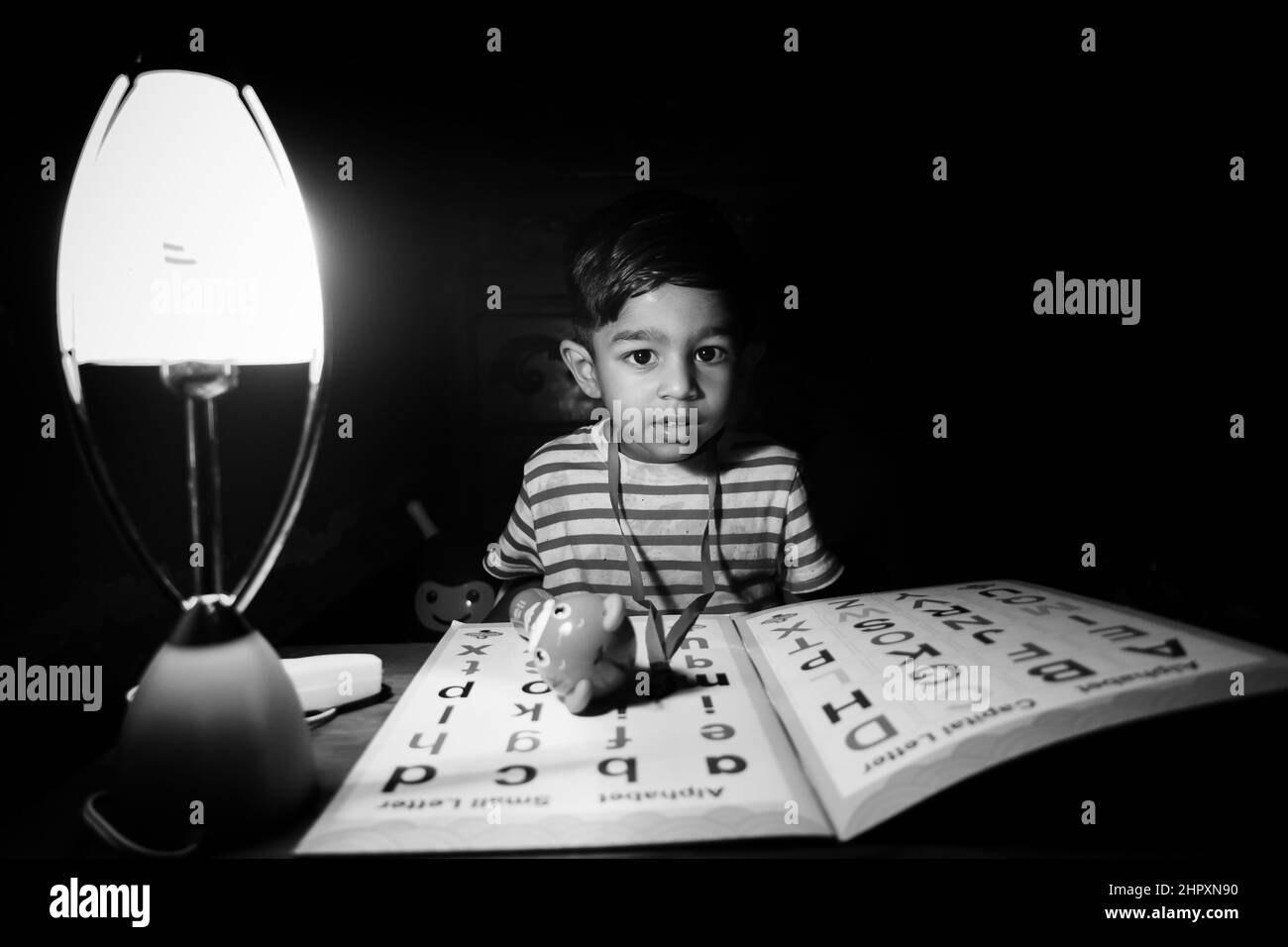 Un garçon apprenant l'alphabet anglais à l'aide d'une lampe de chargeur le soir à la maison. Garçon asiatique étudiant sous la lampe. Photo de concept éducatif enfant. Banque D'Images