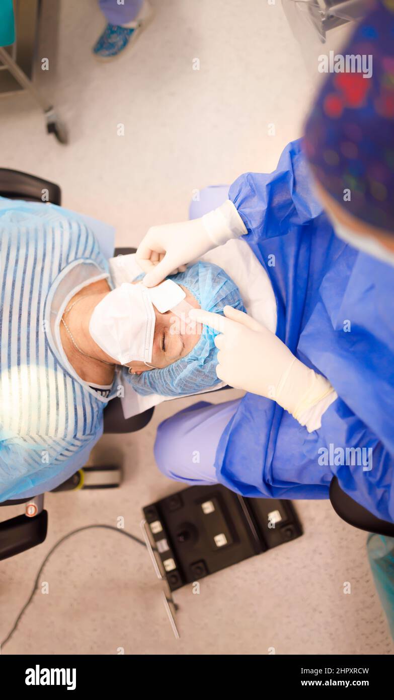 Un patient âgé se pose et attend qu'un médecin mette un timbre oculaire après une opération réussie de la cataracte Banque D'Images