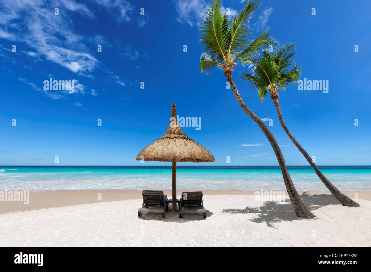 Parasol et chaises de plage sur une plage de sable avec palmiers à coco et mer turquoise. Banque D'Images