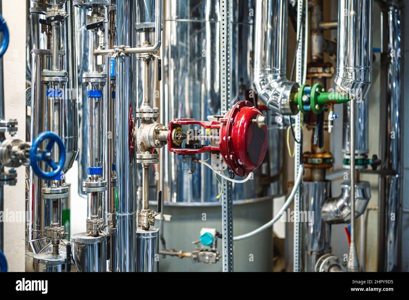 Tuyaux métalliques fins avec petites vannes bleues et brides à l'usine Banque D'Images