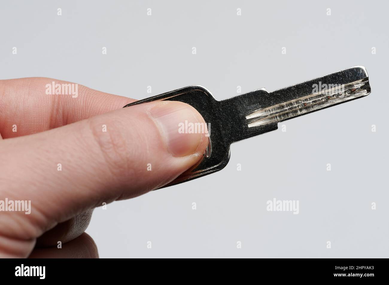 Clé en métal argenté dans la main macro vue rapprochée isolée Banque D'Images