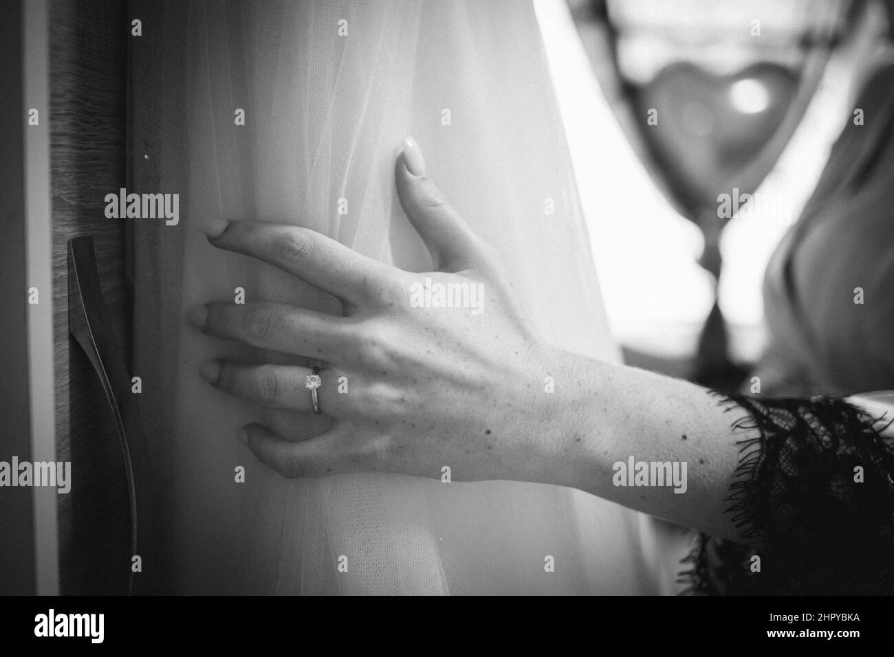 Gros plan en niveaux de gris de la main d'une mariée sur une robe de mariage blanche Banque D'Images