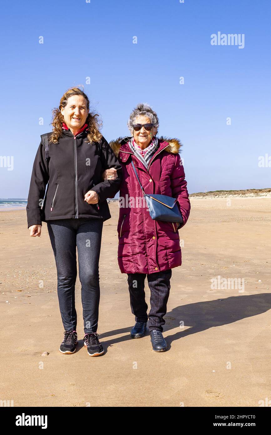 Une femme mûre marchant avec sa mère âgée près de la plage à l'automne Banque D'Images