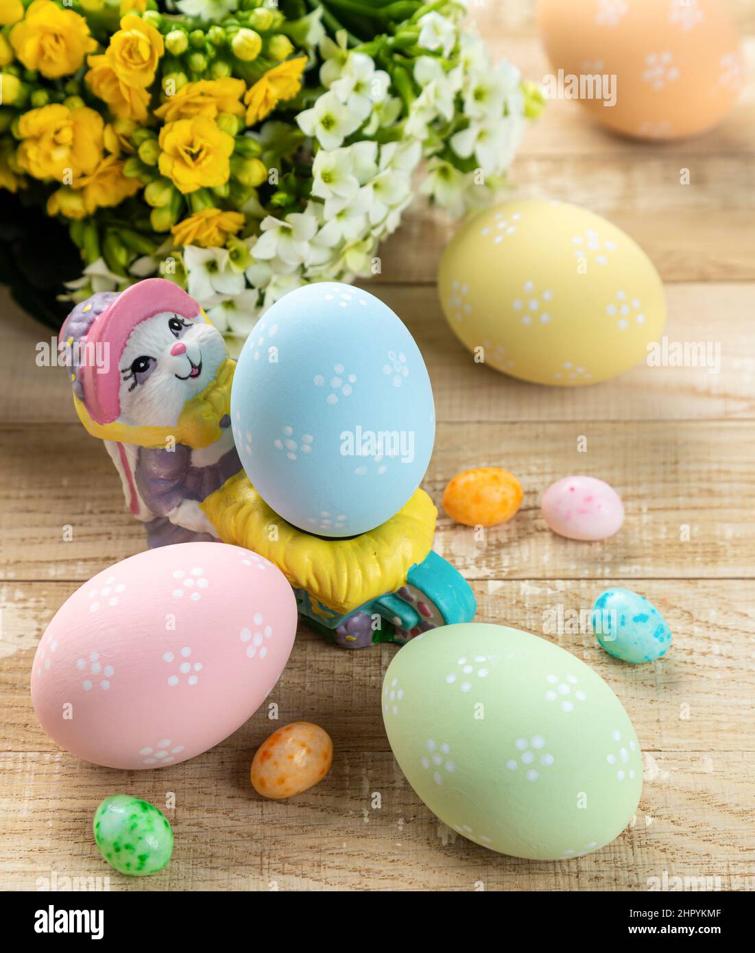 Œufs de pâques colorés, bonbons et fleurs sur une table rustique en bois Banque D'Images