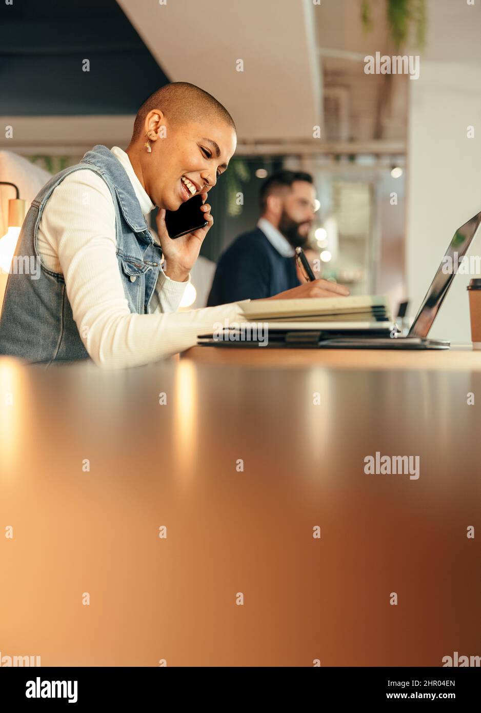 femme d'affaires prenant des notes pendant un appel téléphonique. Jeune femme d'affaires souriant joyeusement tout en faisant des plans avec ses associés. Travail d'entrepreneur féminin Banque D'Images