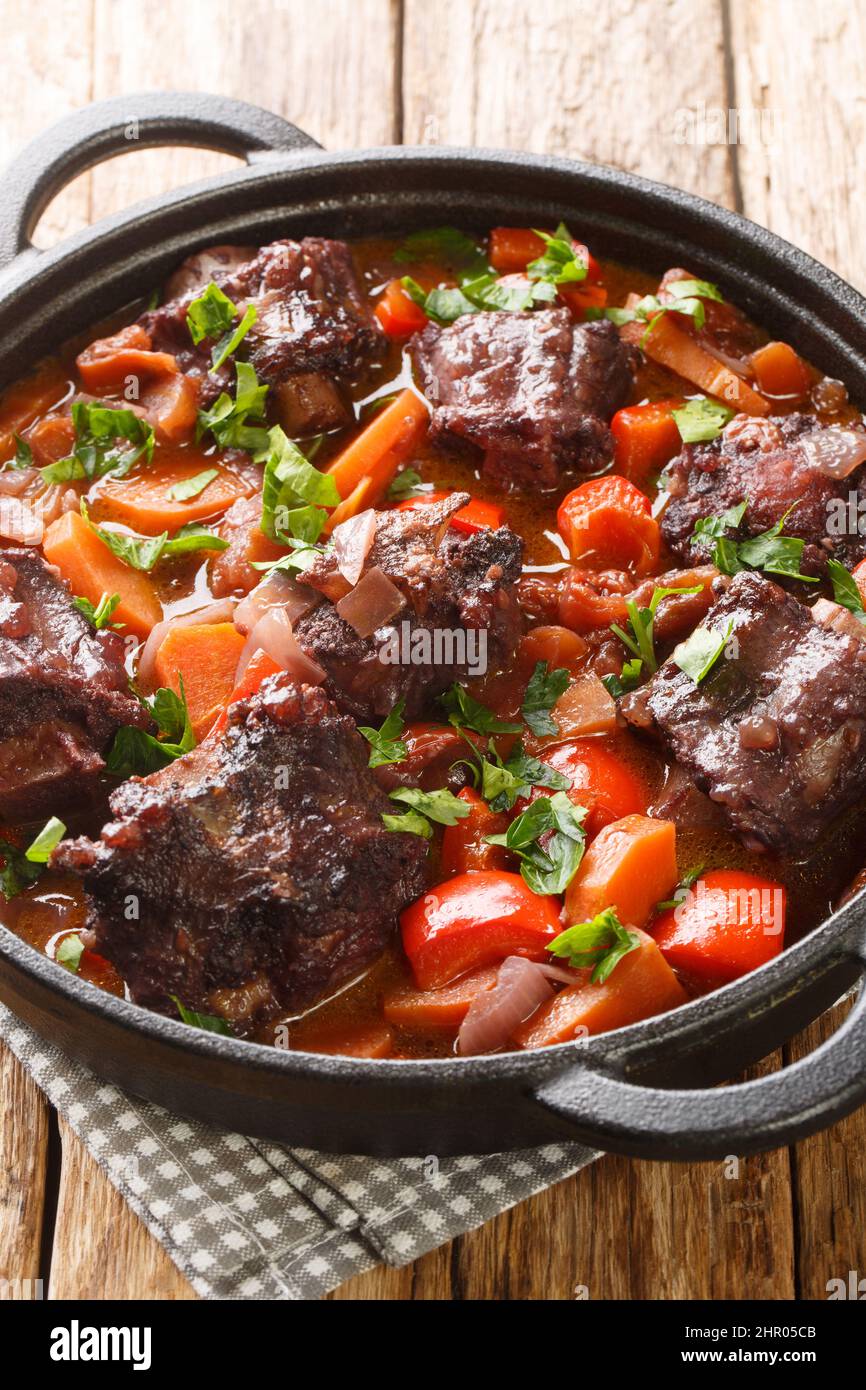 Rabo de toro ou ragoût de queue d'aronde dans une casserole de cuisson près de l'assiette sur la table en bois. Verticale Banque D'Images