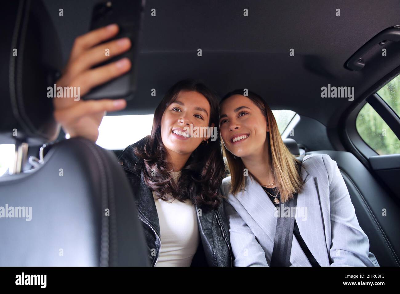 Femmes d'affaires qui se font des affaires pour travailler à l'arrière de la voiture ou de taxi prendre Selfie sur le téléphone mobile Banque D'Images