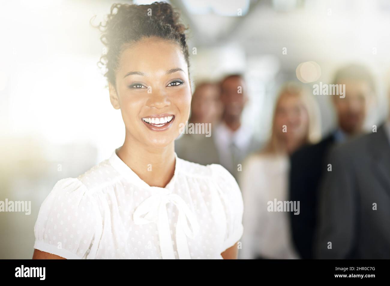 Le succès met toujours un sourire sur mon visage. Portrait court d'une jeune femme d'affaires debout dans son bureau avec des collègues en arrière-plan. Banque D'Images