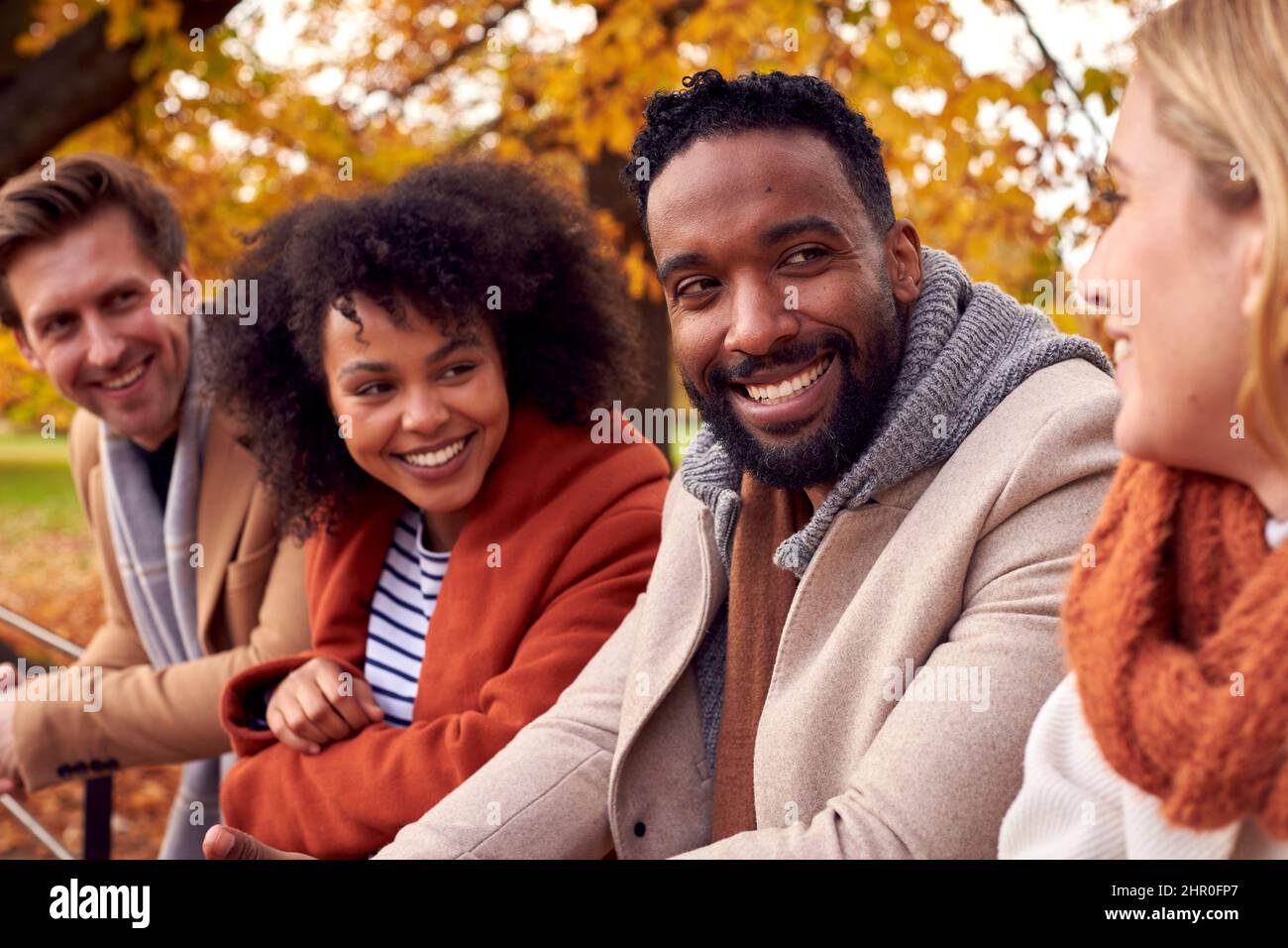Groupe d'amis en plein air portant des manteaux et des Scarves dans le parc d'automne Banque D'Images
