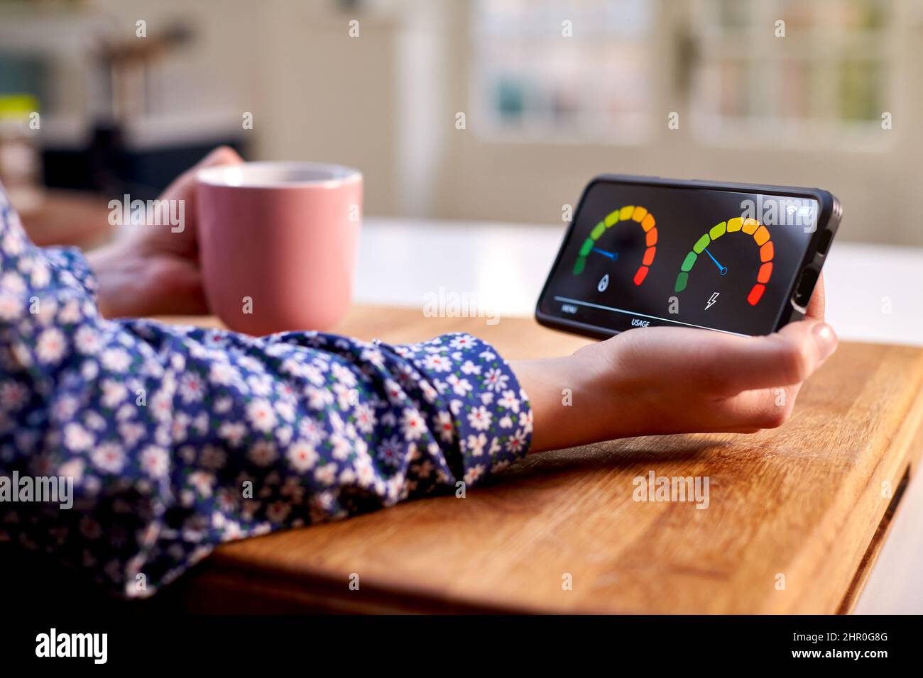 Gros plan d'une femme tenant un compteur d'énergie intelligent dans la cuisine mesure de l'électricité et de la consommation de gaz domestiques Banque D'Images