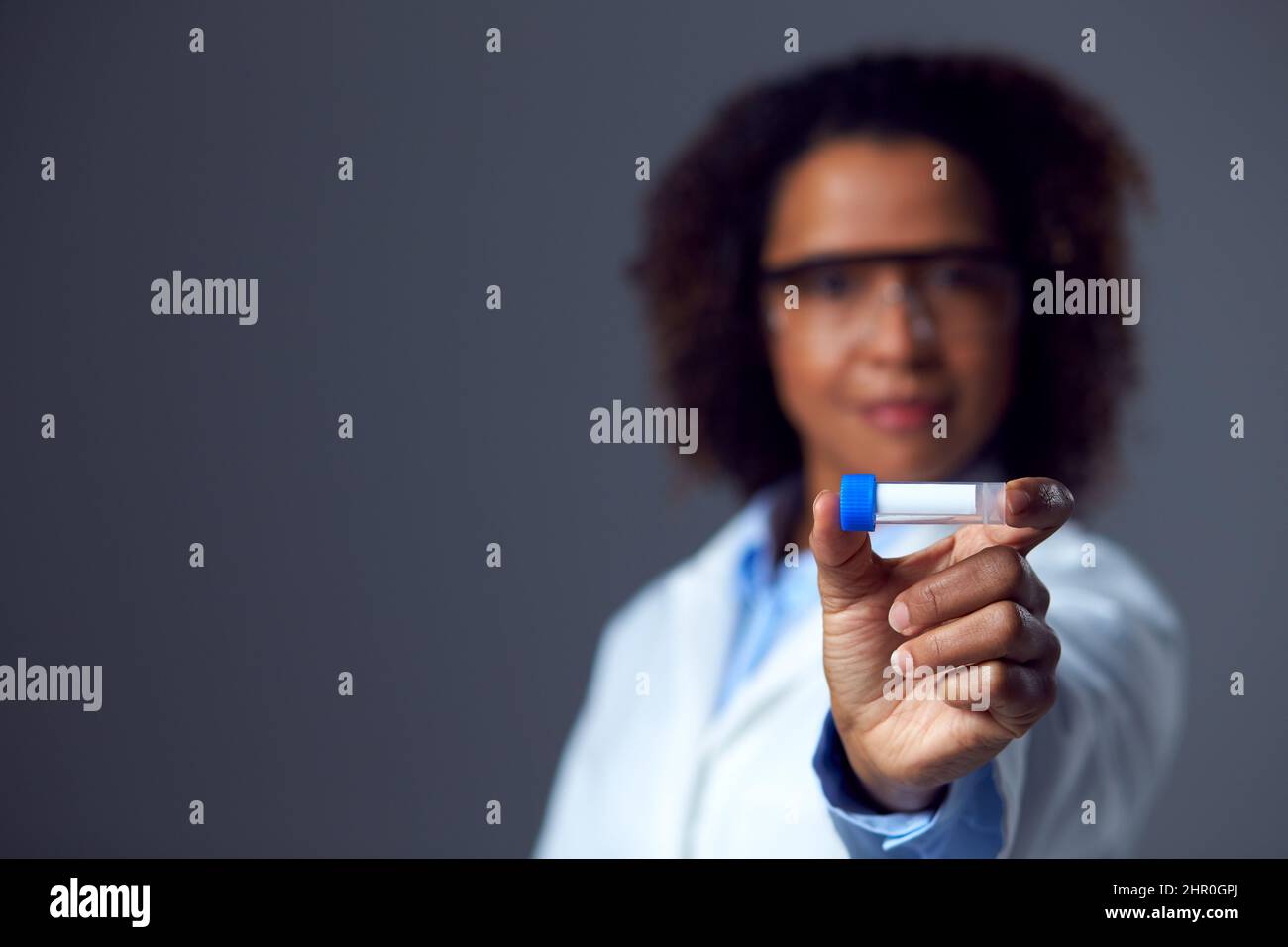 Femme médecin ou travailleur de laboratoire portant un EPI et des lunettes de sécurité contenant un flacon ou un tube à essai Banque D'Images