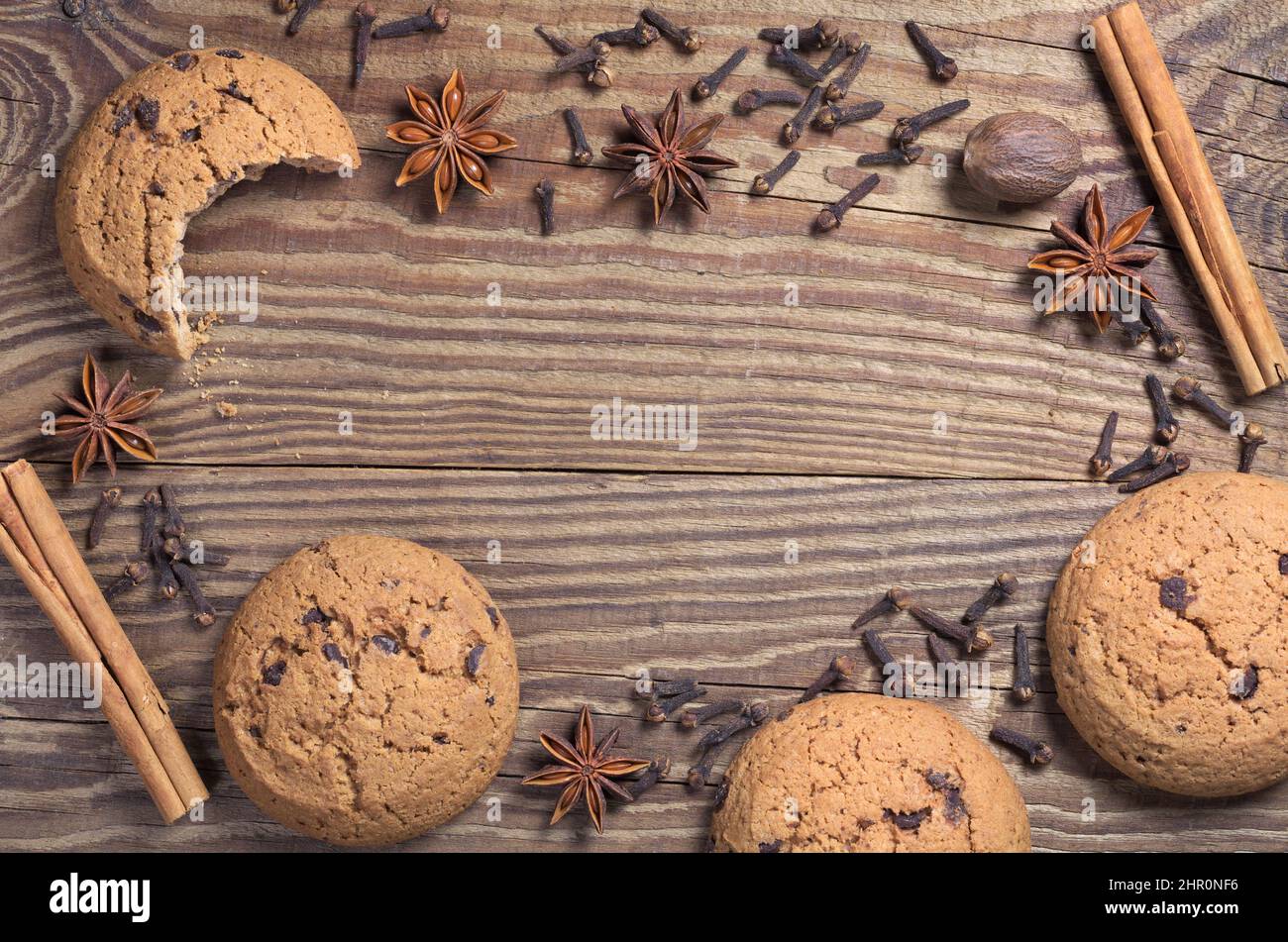 Fond en bois avec biscuits aux flocons d'avoine au chocolat et diverses épices d'hiver. Vue de dessus avec espace pour le texte au milieu Banque D'Images