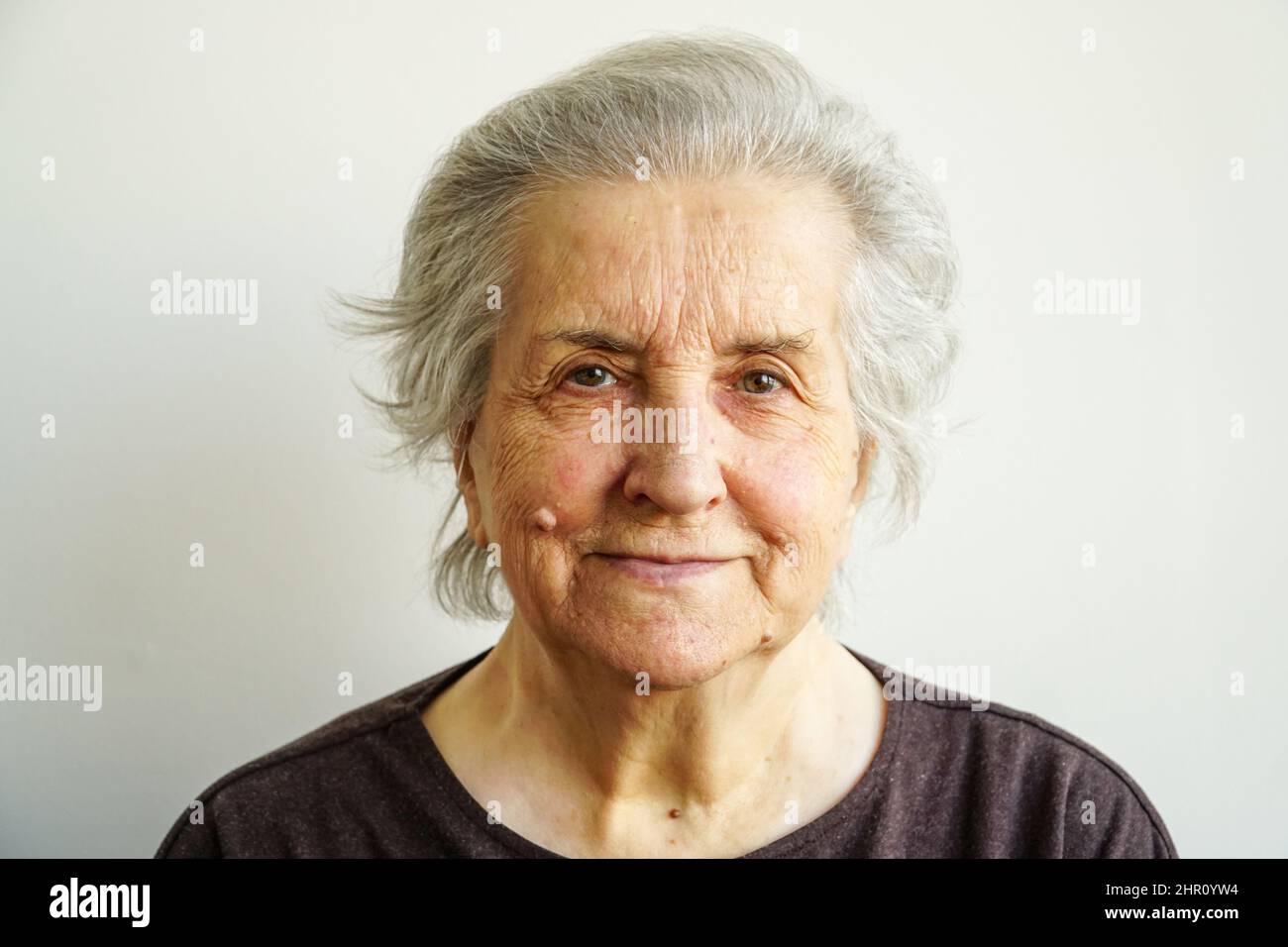 Portrait d'une vieille femme souriante dans les années 70. Vieille femme avec les yeux verts regardant l'appareil photo. Personne âgée souriant paisible. Femme âgée paisible Banque D'Images
