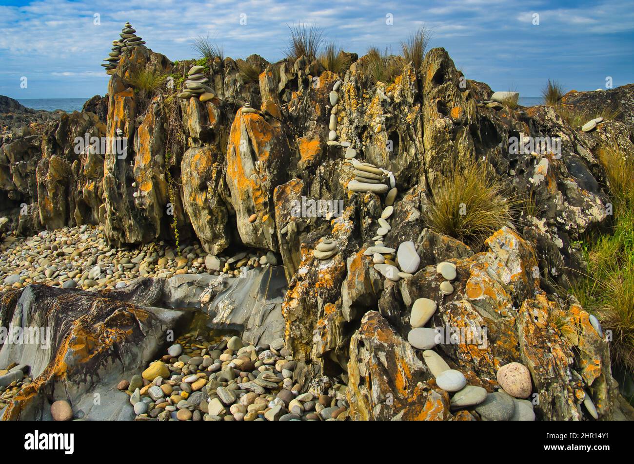 Art terrestre avec piste de galets et cairns sur un rocher couvert de lichen orange à Cape Conran, Victoria, Australie Banque D'Images