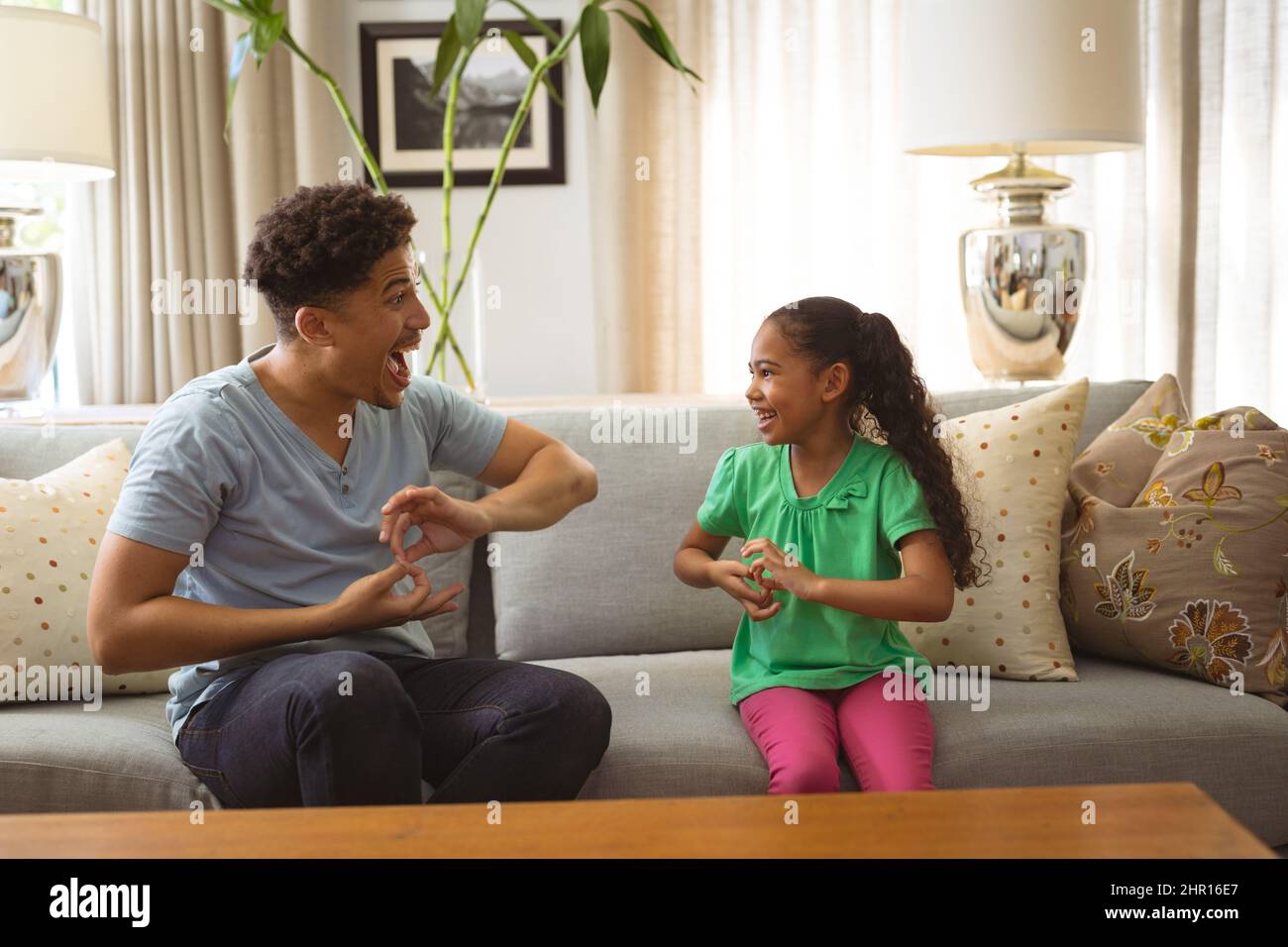 Joyeux père et fille multiracial communiquant par le langage des signes à la maison Banque D'Images