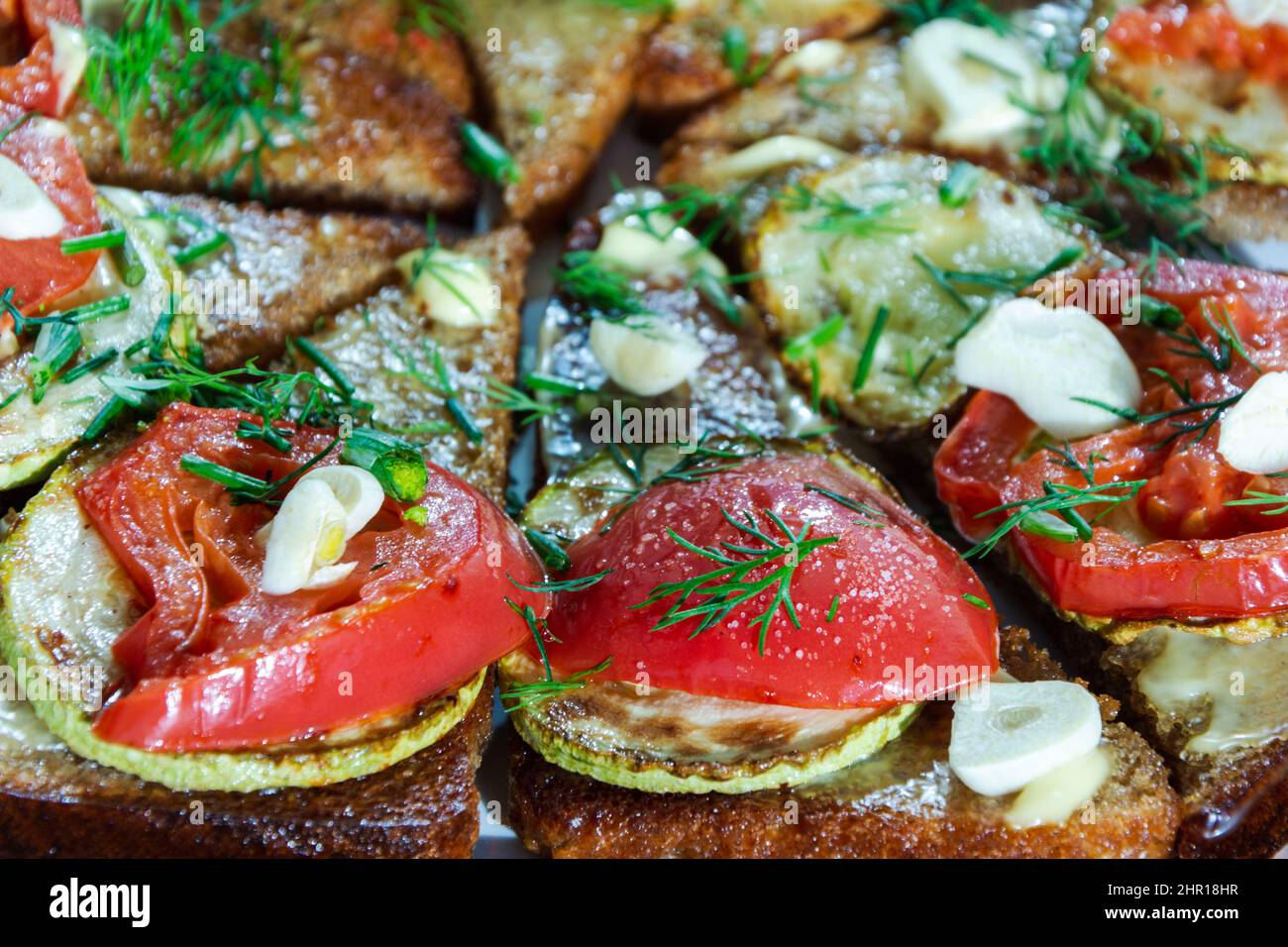 sandwichs frits avec courgettes, tomates et ail, délicieux morceaux de pain noir frits, encas, végétarisme. Banque D'Images