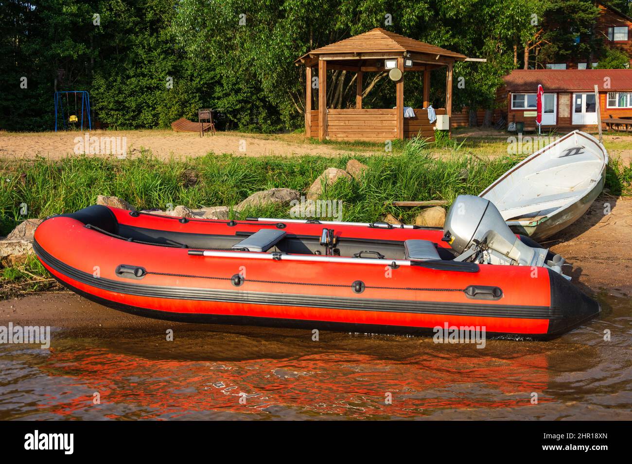 Bateau gonflable rouge en caoutchouc avec un moteur près du bord du lac,  pêche, tourisme, loisirs actifs Photo Stock - Alamy