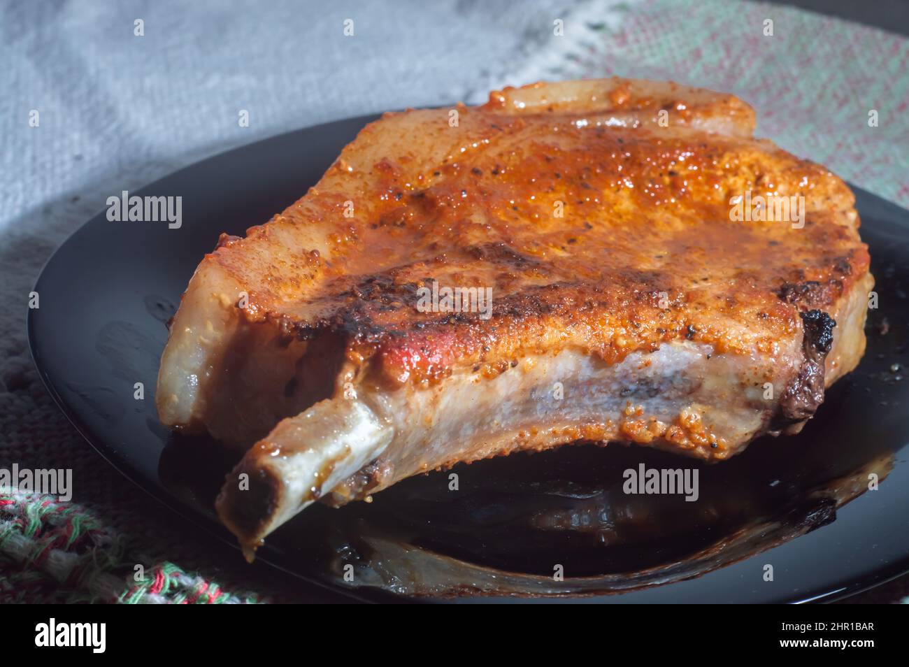 Steak Club. Veau sur l'os. Côtes de viande grillées sur une assiette noire, côte de porc rôtie, avec espace de copie laissé. Banque D'Images
