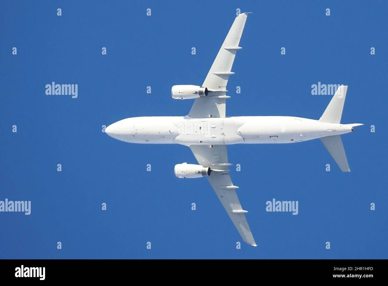 Un avion blanc en vol sur fond bleu ciel, vue de dessous Banque D'Images