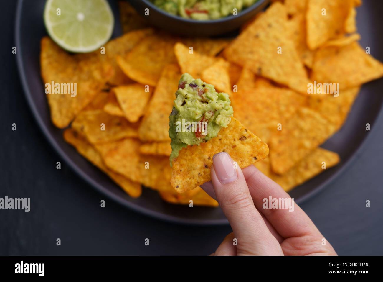 Gros plan de la main de femme avec des nachos et une délicieuse trempette de guacamole fraîche Banque D'Images