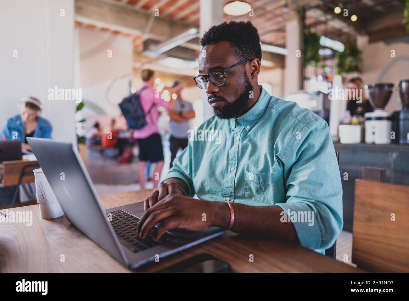 jeune homme noir travaillant sur un ordinateur portable dans un café Banque D'Images