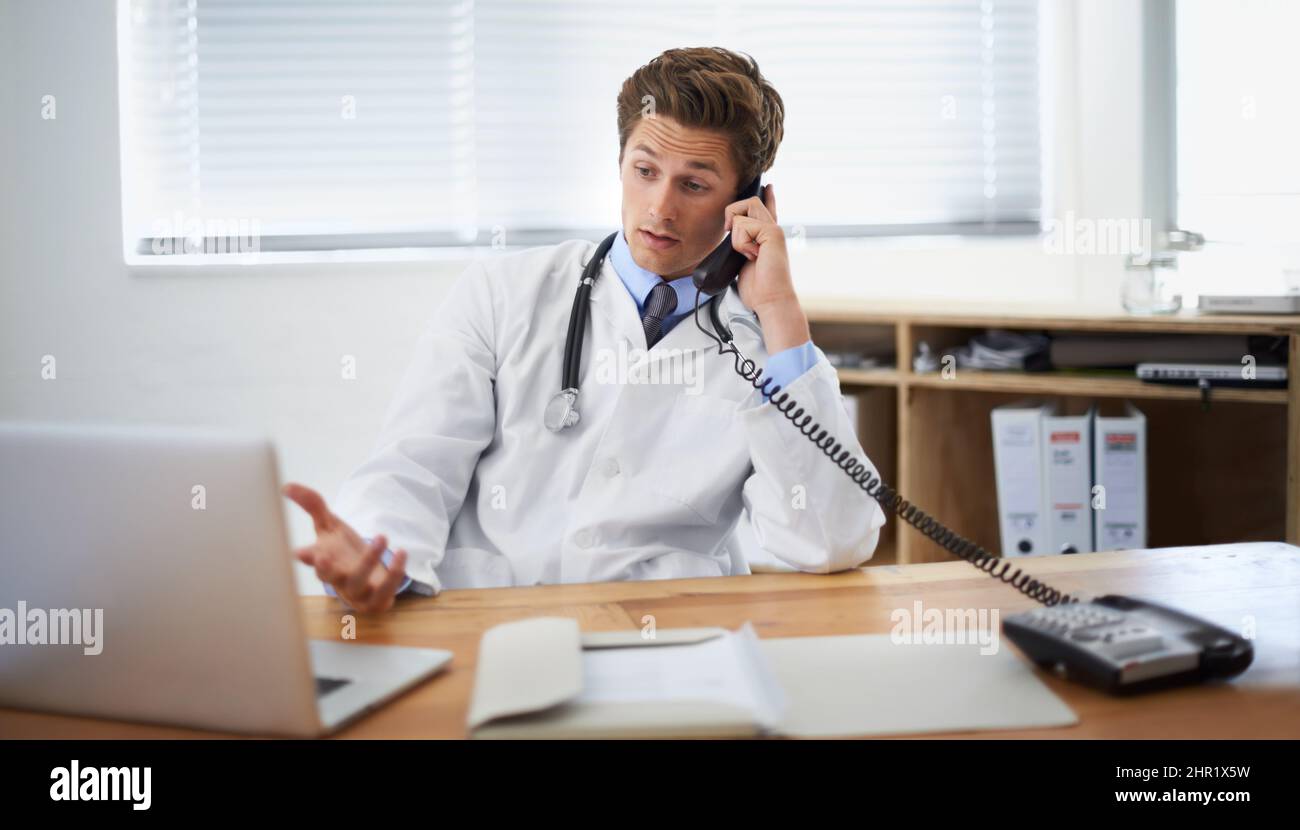 Discuter de l'état d'un patient. Photo d'un jeune médecin assis dans son bureau et parlant au téléphone. Banque D'Images