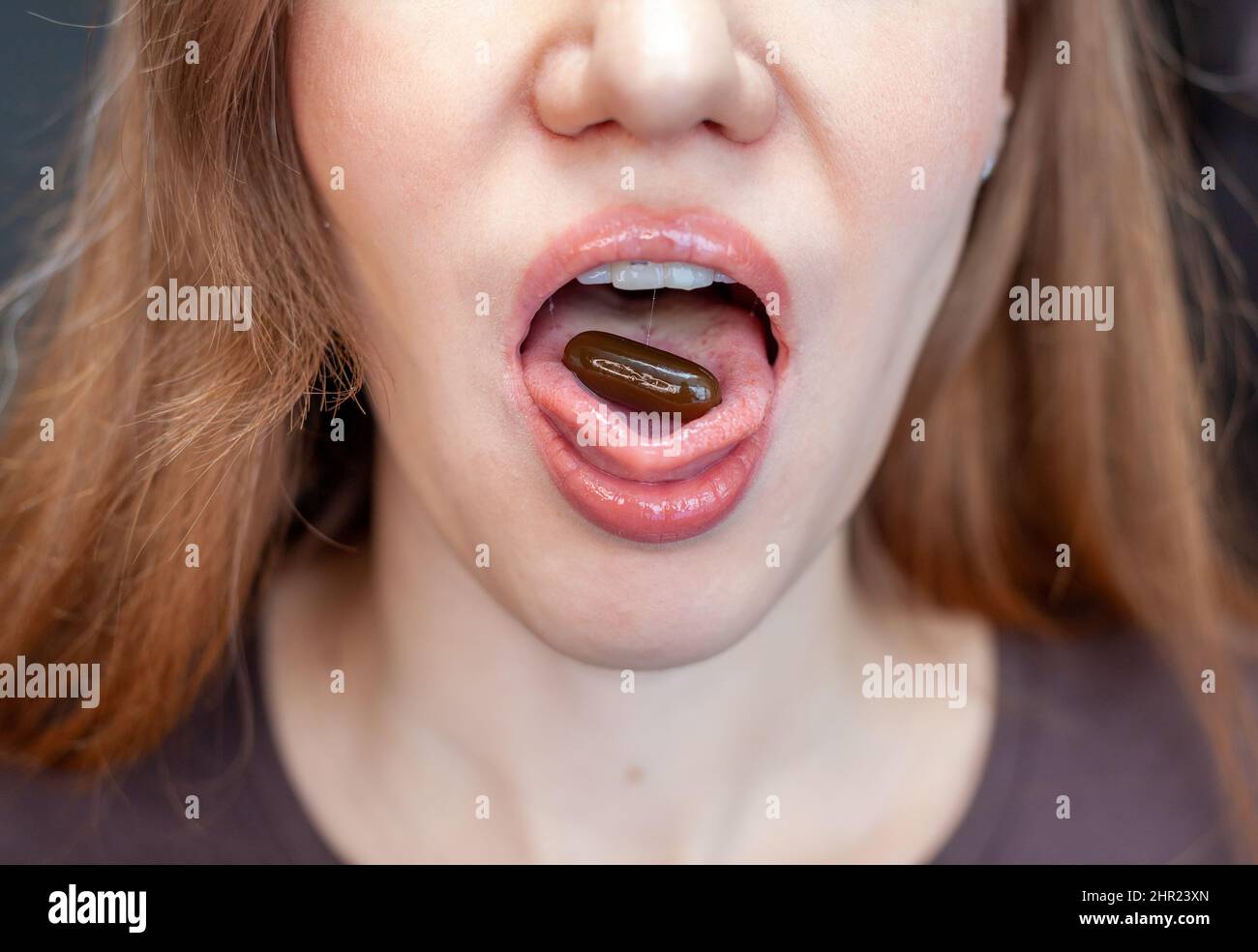 Pilule sur la langue. Gros plan d'une jeune femme tenant la pilule sur sa langue. Belle femme bouche avec pilule sur la langue. Fille prenant la médecine Banque D'Images