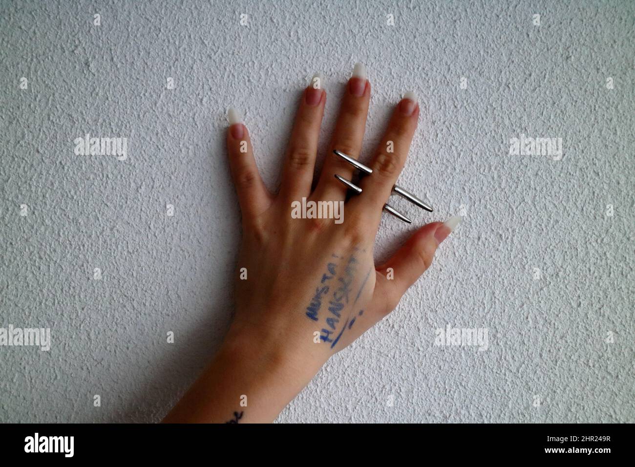 Gros plan d'une main femelle avec de longs ongles de doigt portant l'acier inoxydable Metal Punk Rock Ring Banque D'Images