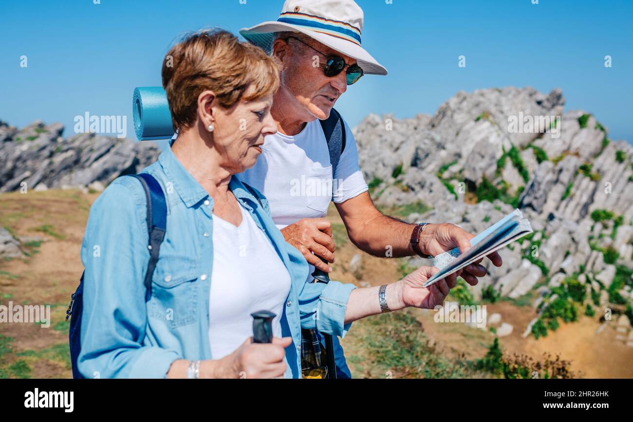 Trekking en couple Senior regardant la carte dans le paysage rocheux Banque D'Images