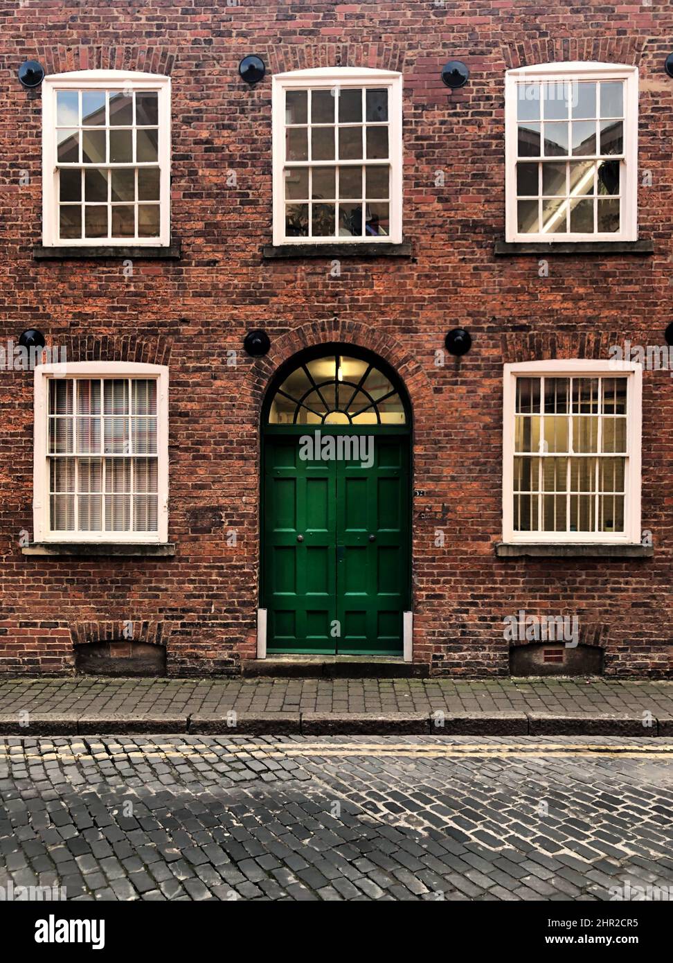 Façade extérieure d'une maison de ville victorienne avec porte verte et fenêtres à guillotine à Granary Wharf à Leeds dans une image d'architecture historique avec espace de copie Banque D'Images