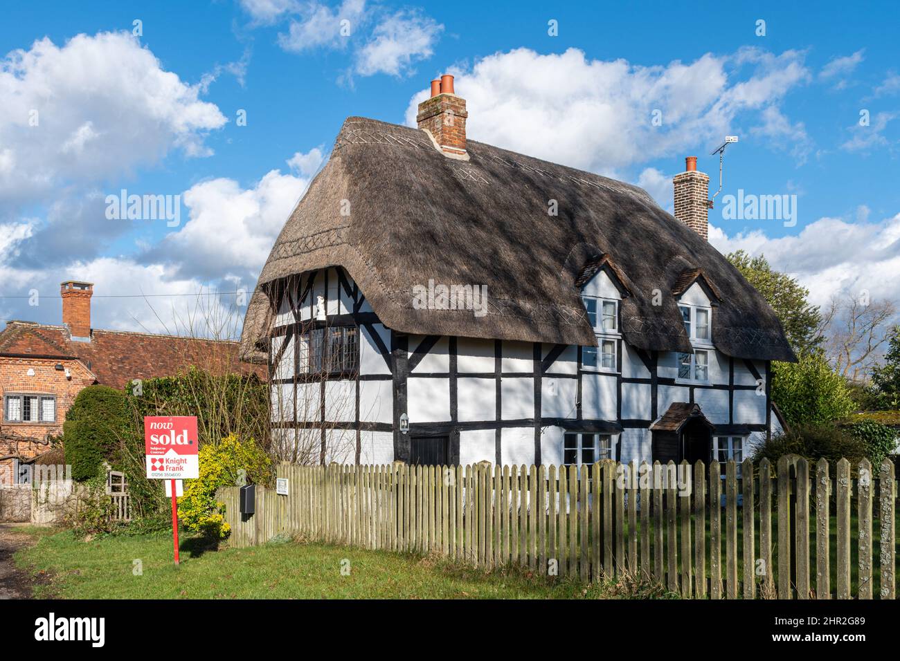 Jolie petite maison de chaume rurale dans le village de Froyle avec signe vendu, Hampshire, Angleterre, Royaume-Uni Banque D'Images