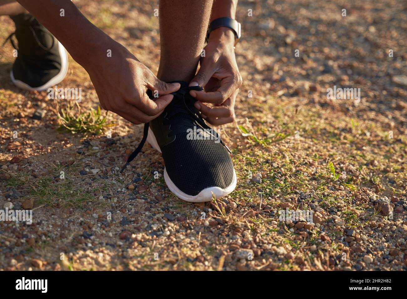 Gros plan de Black jeune adulte athlète masculin nouant ses lacets sur sa chaussure de sport noire. Banque D'Images