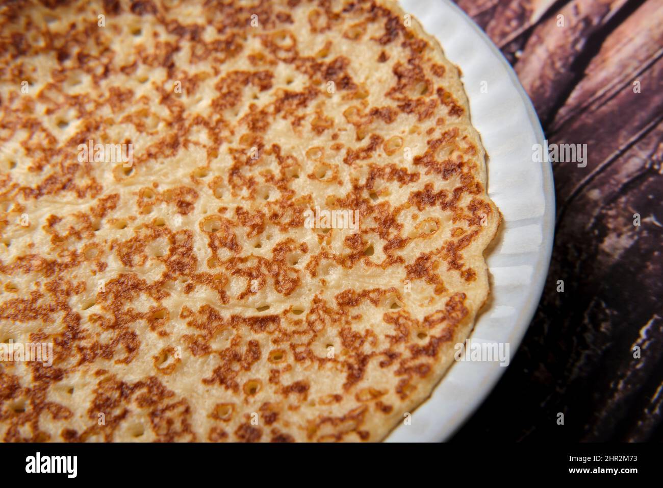 Crêpe douce et unie sur une petite assiette blanche sur un fond en bois de près. Banque D'Images