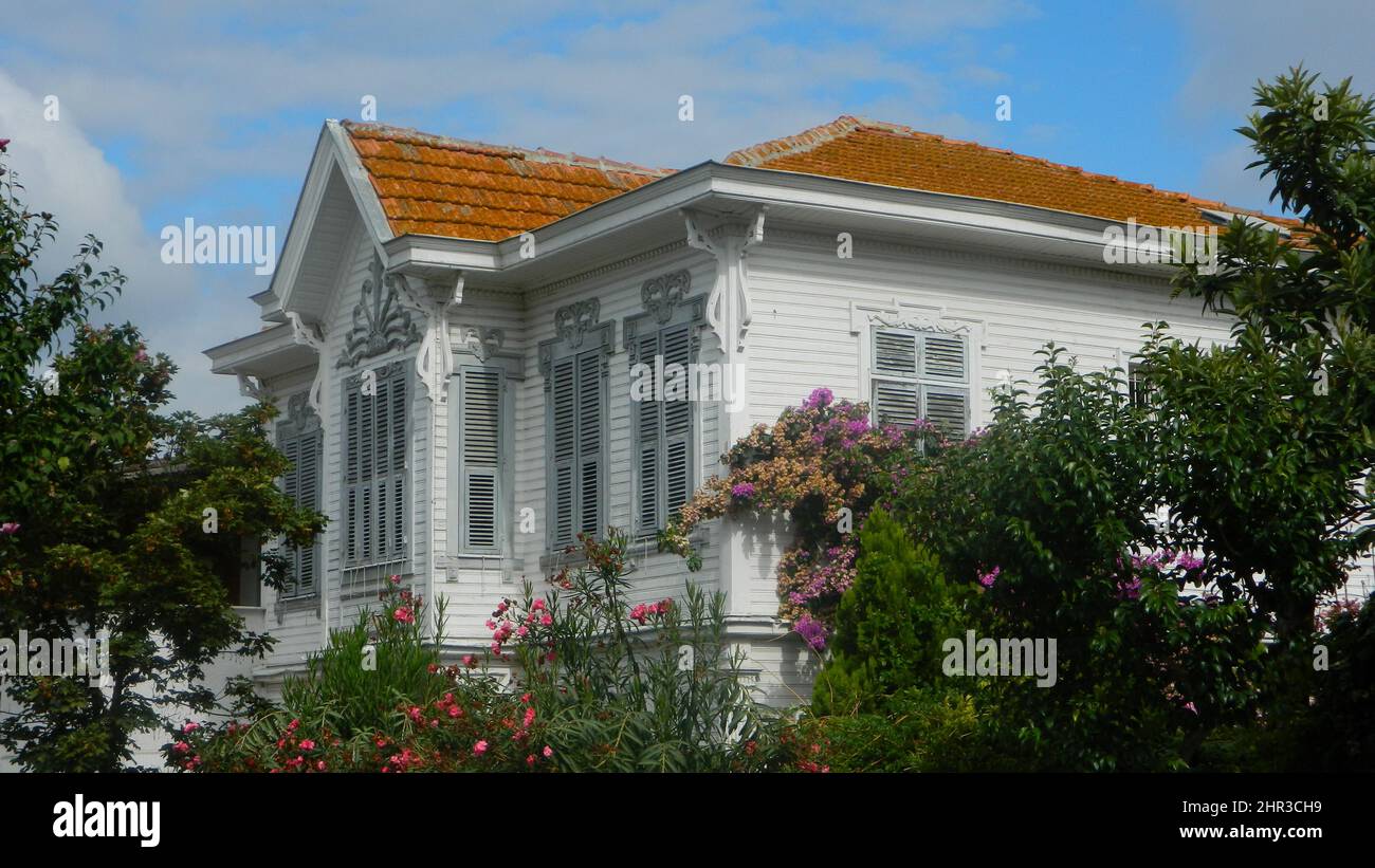 maison en bois blanc, toit ouvrant. petit balcon, grandes fenêtres entourant les arbres verts Banque D'Images