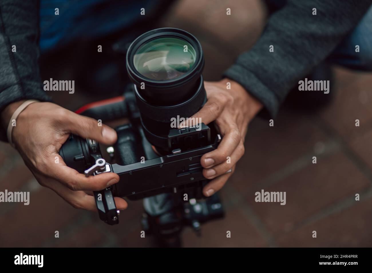 Photographe réglant une caméra DLSR sans miroir de Sony montée sur une nacelle Ronin S sur un trottoir Banque D'Images
