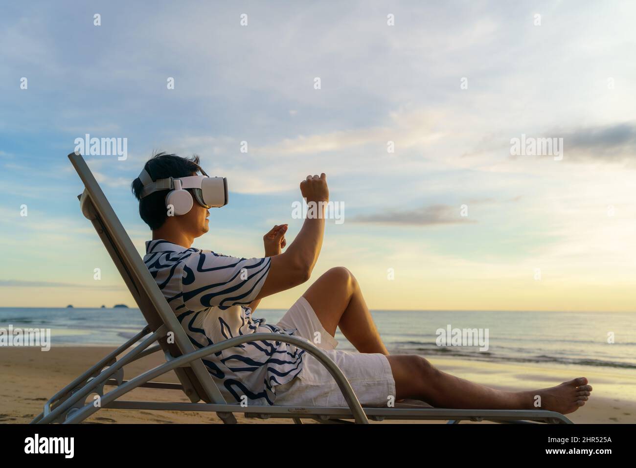 Jeune homme asiatique utilisant des lunettes de réalité virtuelle pour les réunions d'affaires sur la plage tropicale sur un magnifique fond de mer et de ciel Banque D'Images